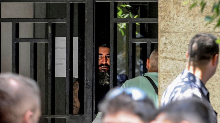 11 August 2022, Lebanon, Beirut: An armed depositor speaks to negotiators from behind the iron bars of a local Bank in Beirut after he stormed the branch and held employees and customers as hostages. The man, who entered the bank carrying a machine gun and gasoline, demanded to be handed over part of his deposited money, which amounts to USD&#39;209,000. Protests erupted in Lebanon in 2019 amid a financial crisis that led banks to tightened withdrawal limits on foreign currency to USD&#39;200-300 per we