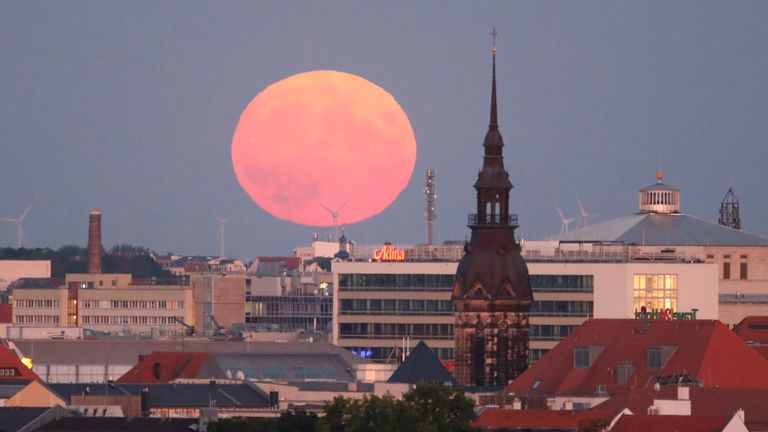 11 August 2022, Saxony, Leipzig: The moon rises behind the city center.  Photo by: Sebastian Willnow/picture-alliance/dpa/AP Images PIC:AP