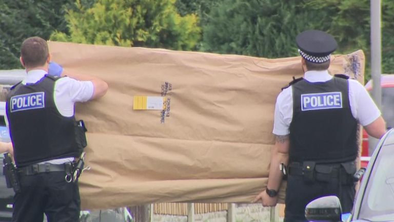 Police carry a door away from the murder scene