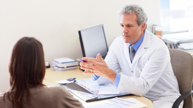 Mature doctor sitting at his desk and consulting with a patient