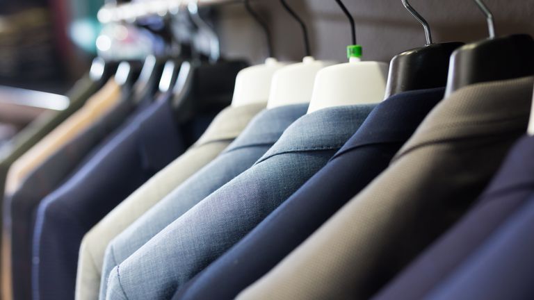 Assortment of suit jackets on hanger racks in menswear store for sale