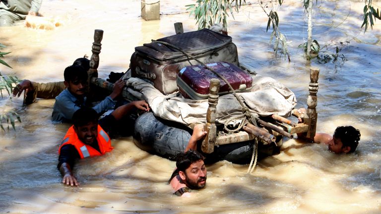 People float their belongings through a flooded area on the outskirts of Peshawar.  Photo: AP