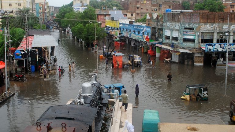Haydarabad, Pakistan'da, 24 Ağustos 2022 Çarşamba, şiddetli muson yağmurlarının ardından insanlar su basmış yollardan geçiyor. (AP Photo/Pervez Masih)