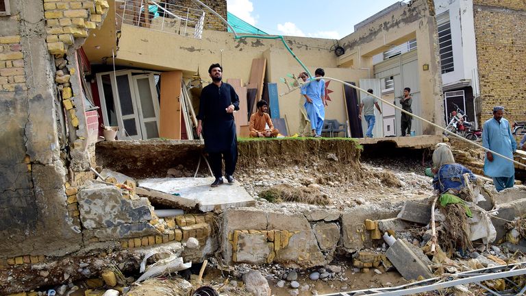 Les gens se tiennent dans leurs maisons partiellement endommagées par les inondations après de fortes pluies, à la périphérie de Quetta, au Pakistan, le samedi 27 août 2022. Les responsables affirment que les inondations soudaines déclenchées par les fortes pluies de mousson dans une grande partie du Pakistan ont tué près de 1 000 personnes et déplacés des milliers d'autres depuis la mi-juin.  (AP Photo/Arshad Butt) PIC: AP