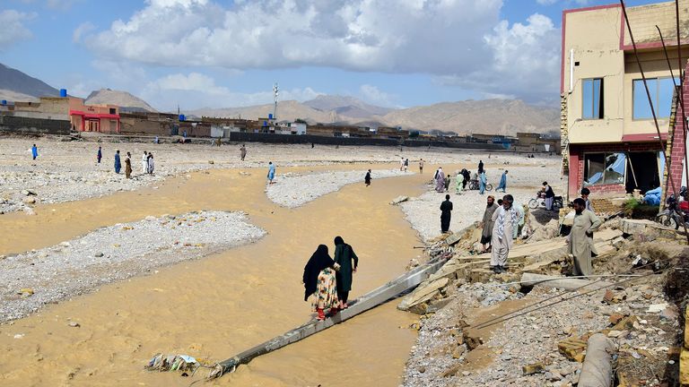 Les gens se tiennent dans leurs maisons partiellement endommagées par les inondations après de fortes pluies, à la périphérie de Quetta, au Pakistan, le samedi 27 août 2022. Les responsables affirment que les inondations soudaines déclenchées par les fortes pluies de mousson dans une grande partie du Pakistan ont tué près de 1 000 personnes et déplacés des milliers d'autres depuis la mi-juin.  (AP Photo/Arshad Butt) PIC: AP