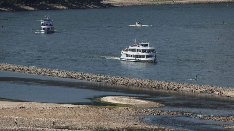 People stroll on the dried riverbed of the Rhine river as tourist vessels cruise Europe&#39;s most frequented waterways in Bingen, Germany, August 9, 2022. REUTERS/Wolfgang Rattay
