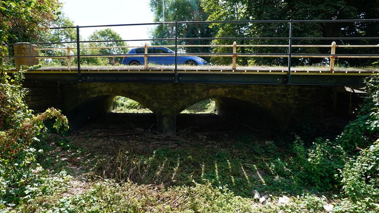 A car passes over a bridge over a dried up river bed where the River Thames flows near to Kemble in Gloucestershire, as parched parts of England are facing a hosepipe ban amid very dry conditions and ahead of another predicted heatwave. Months of little rainfall, combined with record-breaking temperatures in July, have left rivers at exceptionally low levels, depleted reservoirs and dried out soils. Picture date: Friday August 5, 2022.

