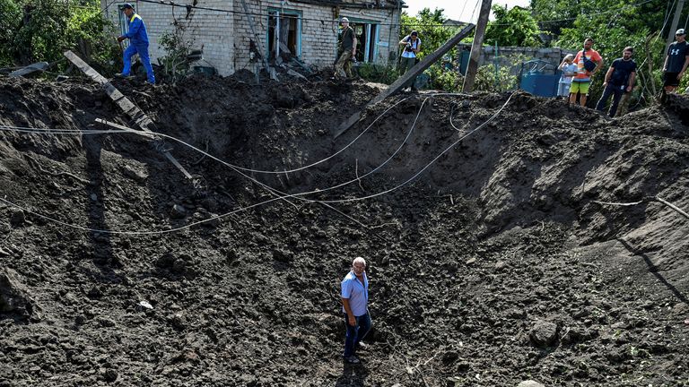 A man stands inside a crater left by a Russian missile strike in the settlement of Kushuhum, as Russia&#39;s attack on Ukraine continues, in Zaporizhzhia region, Ukraine August 10, 2022. REUTERS/Dmytro Smolienko/File Photo