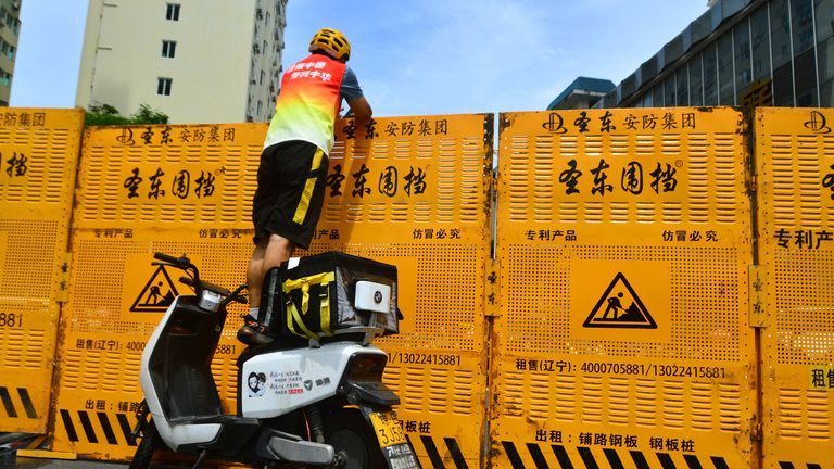 A courier tries to make a delivery over a lockdown barricade in Sanya