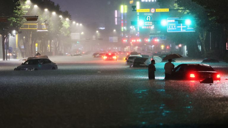 Men stand among vehicles abandoned in flooded area during heavy rain in Seoul, South Korea, August 8, 2022. Yonhap via REUTERS ATTENTION EDITORS - THIS IMAGE HAS BEEN SUPPLIED BY A THIRD PARTY. SOUTH KOREA OUT. NO RESALES. NO ARCHIVE.
