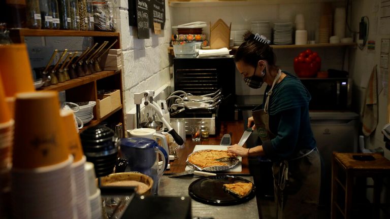 Paulina Filippou serves Spanakopita, the Greek word for spinach pie, in her &#39;Isle of Olive&#39; Natural Greek Products store and delicatessen, which can stay open for takeaway food and drink and online orders during England&#39;s second coronavirus lockdown, on Ada Street, off Broadway Market in Hackney, east London, Tuesday, Nov. 17, 2020. Small businesses all over the world are struggling to cope as the coronavirus forces changes in consumer habits, but the U.K. also faces uncertainty of the Brexit sp