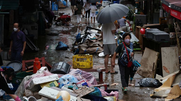 People make their way through a road that was flooded after torrential rain, at a traditional market in Seoul, South Korea, August 9, 2022. REUTERS/Kim Hong-Ji
