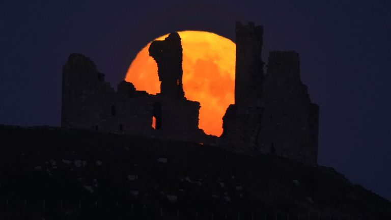 The Sturgeon supermoon, the final supermoon of the year rises over Dunstanburgh Castle in Northumberland. Picture date: Thursday August 11, 2022.
