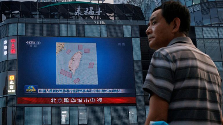 A man stands in front of a CCTV screen showing a map of locations around Taiwan where the People's Liberation Army (PLA) conducts military exercises and training activities including including live-fire drills, at a central shopping district in Beijing, China, August 3, 2022. REUTERS / Thomas Peter / File Photo