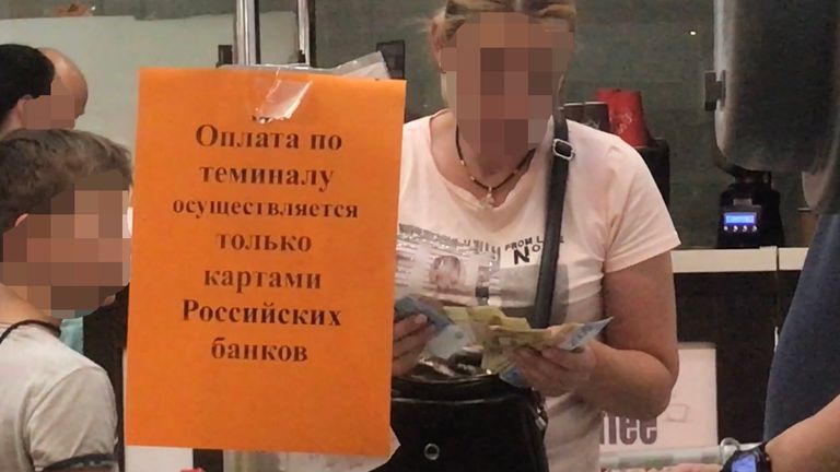 El letrero naranja dice que solo se aceptan tarjetas de bancos rusos en la tienda en Kherson.  Muchos bancos ucranianos han sido cerrados haciendo la vida mucho más difícil.
