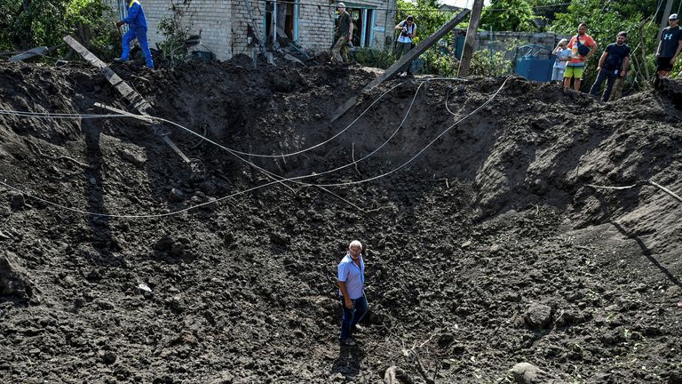 Un homme se tient à l'intérieur d'un cratère laissé par une frappe de missile russe dans la région de Zaporizhzhia