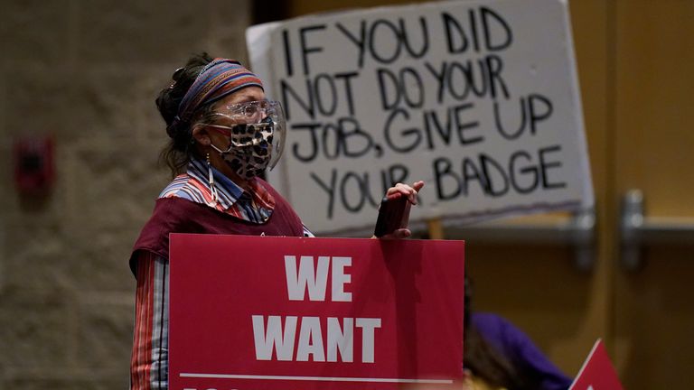 Parents and family members hold signs at a meeting of the Board of Trustees of the Uvalde Consolidated Independent School District