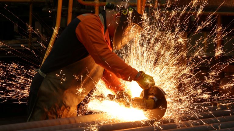 A worker cuts newly manufactured bars of steel at the United Cast Bar Group&#39;s foundry in Chesterfield, Britain, April 12, 2022
