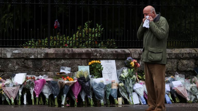 A person reacts near floral tributes by an entrance to Balmoral Castle, following the passing of Britain&#39;s Queen Elizabeth, in Balmoral, Scotland, Britain, September 9, 2022. REUTERS/Russell Cheyne
