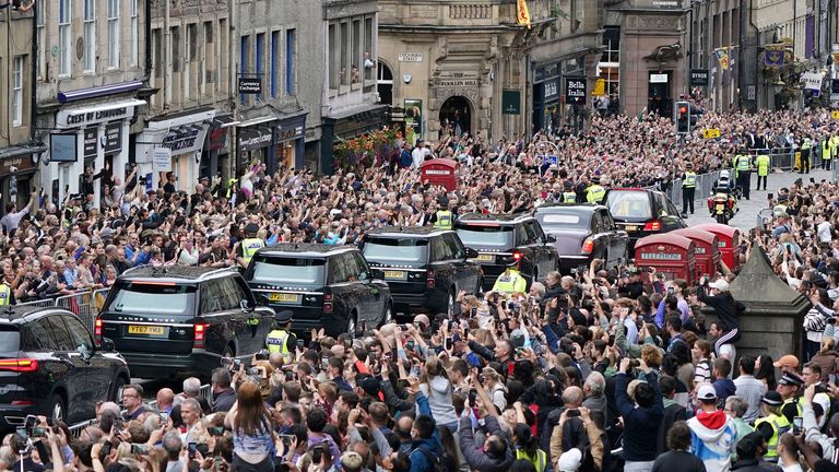 Crowds watch as the hearse carrying Queen Elizabeth II's coffin, dressed in Scottish Royal Standard, passes the Mercat Cross in Edinburgh, Sunday, September 11, 2022, as it continues its journey to the Palace Holyroodhouse from Balmoral.  (Ian Forsyth / Pool photo via AP)