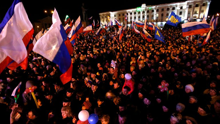 People wave Russian and Crimean flags as they wait for the announcement of the preliminary results of the referendum in the Crimean capital of Simferopol on March 16, 2014