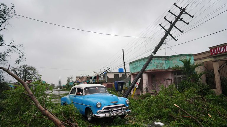 A vintage car passes by debris caused by the Hurricane Ian as it passed in Pinar del Rio, Cuba, September 27, 2022. REUTERS/Alexandre Meneghini