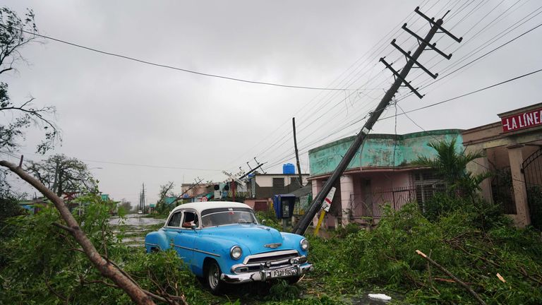 A vintage car drives through debris caused by Hurricane Ian as it passed through Pinar del Rio, Cuba, September 27, 2022. REUTERS/Alexandre Meneghini