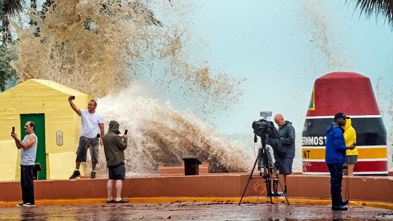 News crews, tourists and local residents take pictures as high waves from Hurricane Ian crash into the seawall at the Southernmost Point Buoy, Tuesday, Sept. 27, 2022, in Key West, in Florida.  Ian was expected to strengthen even more on the warm Gulf of Mexico waters, reaching peak winds of 140 mph (225 km/h) as it approached the southwest coast of Florida.  (Rob O'Neal/The Key West Citizen via AP)