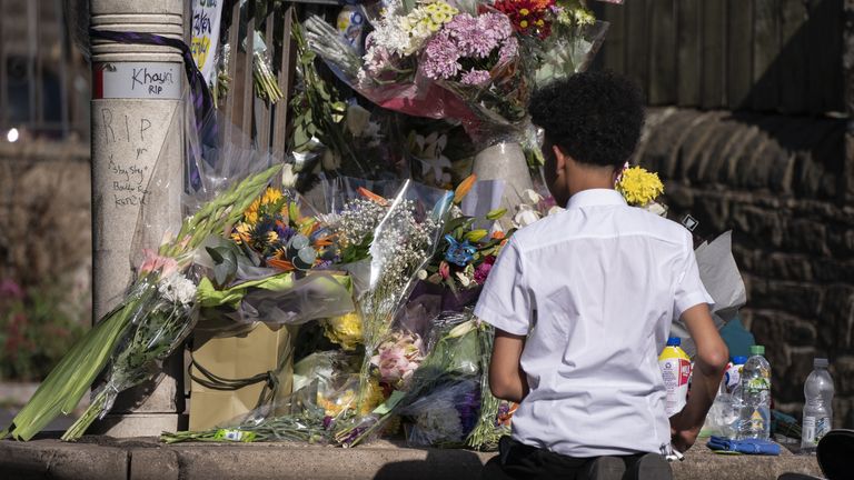 A pupil views floral tributes at the scene in Woodhouse Hill, Huddersfield, where 15-year-old schoolboy Khayri McLean was fatally stabbed outside his school gates. Picture date: Friday September 23, 2022.