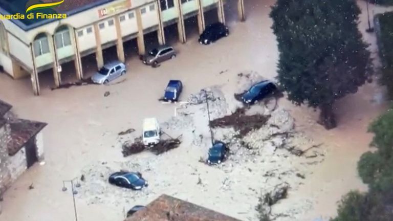 Partially submerged cars on a flooded street in the region of Marche 