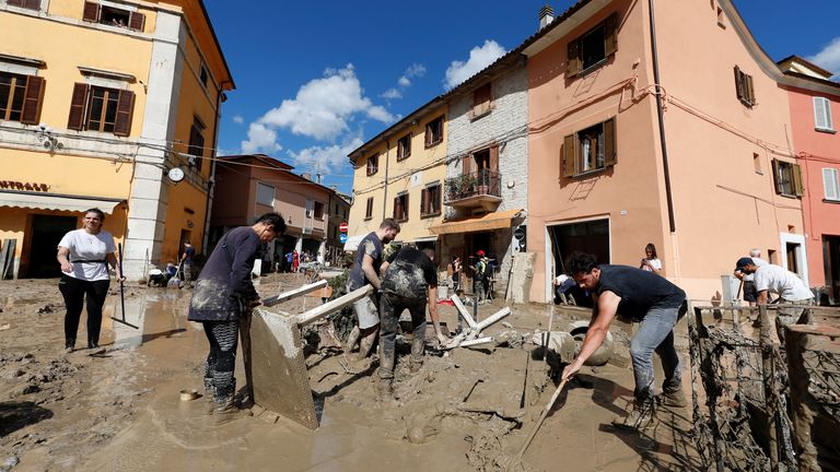 People working to clean up debris and mud left behind after the deadly floods that hit Cantiano in the Marches 