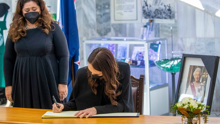 New Zealand Prime Minister Jacinda Ardern, right, signs the book of condolences as Governor-General Dame Cindy Kiro watches. Pic: AP