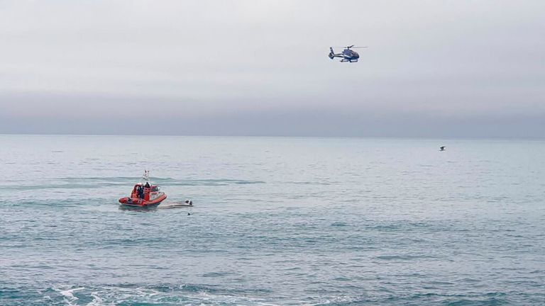 A helicopter and a rescue boat search for survivors off the coast of Kaikoura