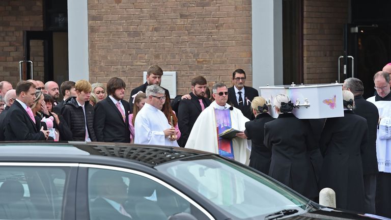 Mourners, many of whom were wearing the pinks that had been requested, enter the church in Knotty Ash