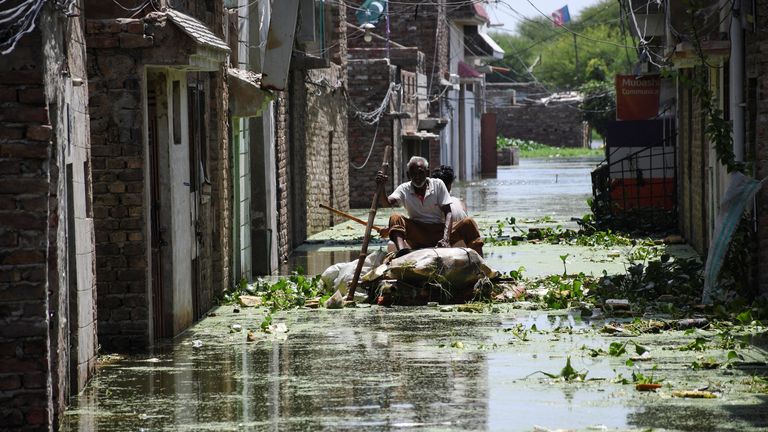 Men use a makeshift raft as they cross a flooded street in a residential area, following rains during the monsoon season in Hyderabad