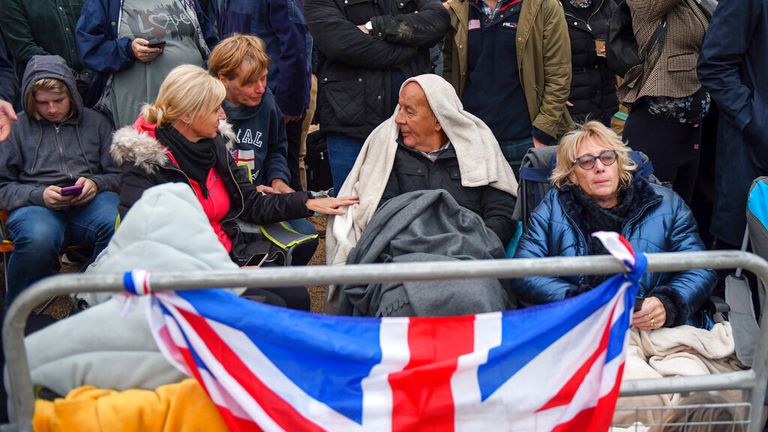 Mourners have wrapped themselves in blankets as they prepare to pay their respects - with one keen to keep his head warm on a chilly September morning. Pic: AP