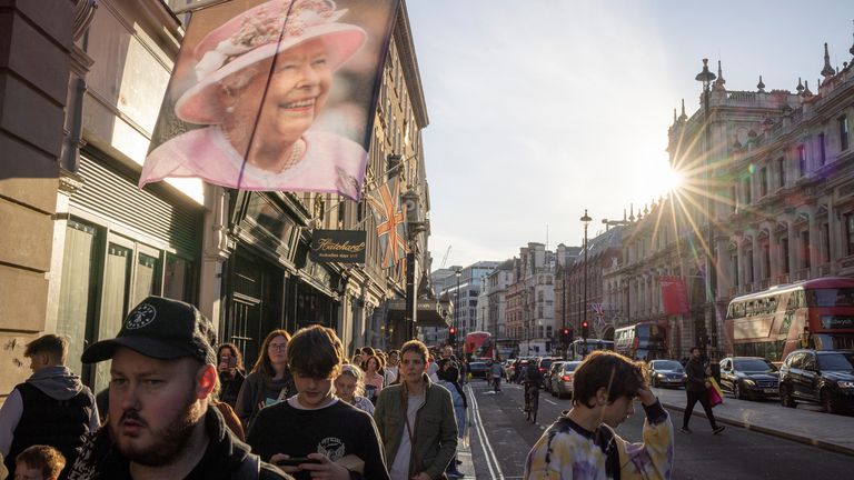 Pedestrians walk past a banner with a portrait of Britain&#39;s Queen Elizabeth, following her death, in London, Britain, September 17, 2022. REUTERS/Marko Djurica