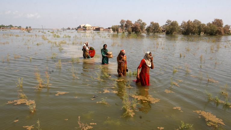 パキスタンの女性​​は、2022 年 9 月 2 日金曜日、パキスタンのシンド州のシカルプール地区に避難しながら、洪水の中を歩きます。写真: AP