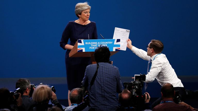 A member of the audience hands British Prime Minister Theresa May a P45 (termination tax form) form as she addresses the Conservative Party Conference in Manchester