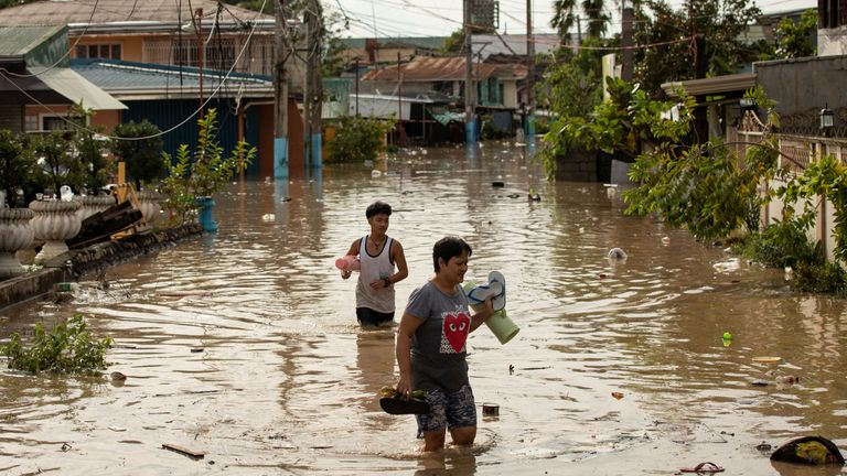 Residents wade through waist-deep flood waters after Typhoon Noru, in San Miguel, Bulacan province, Philippines