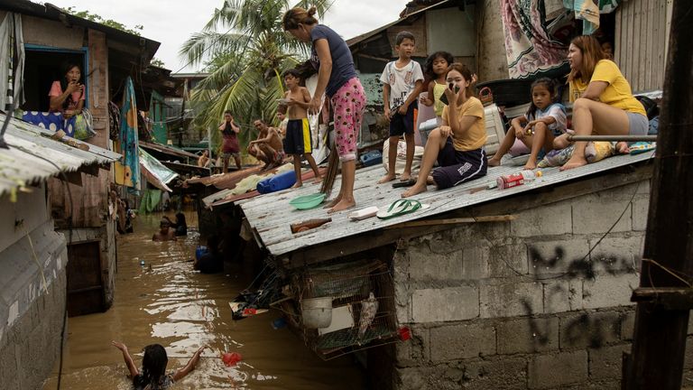 Residents wait on the roof of their homes for flooding to subside