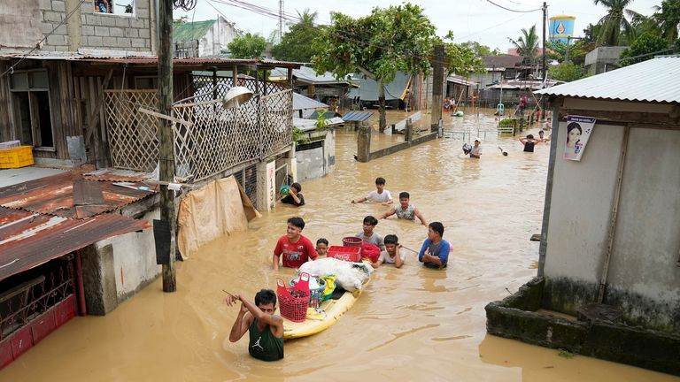 Residents wade through a flooded street in San Miguel town, Bulacan province, Philippines