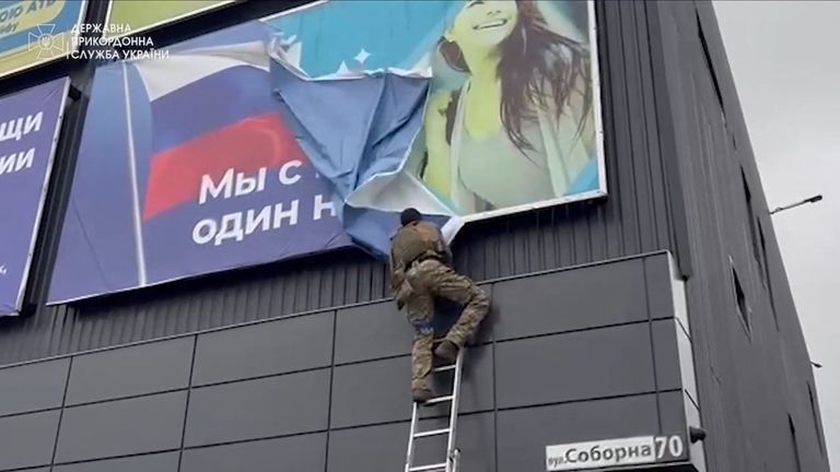 A Ukrainian soldier tears a Russian banner, in Vovchansk Pic: State Border Service of Ukraine