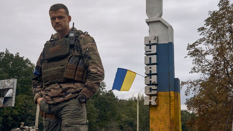 A Ukrainian soldier stands near the sign reading "Kupiansk" in the recently retaken Kupiansk in the Kharkiv region. Pic: AP