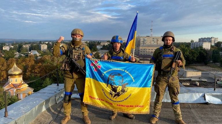 Ukrainian soldiers hold a flag on a rooftop in Kupiansk, Ukraine in this photo taken from social media released on September 10, 2022. Telegram @ kuptg / via REUTERS THIS IMAGE HAS BEEN SUPPEDED A THIRD PARTY GRANT.  CREDIT MANDATORY.  NO ANSWER.  NO STOCK.