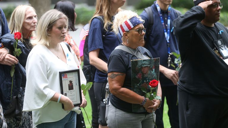 Family attends a memorial service in Manhattan, holding pictures of their lost loved ones