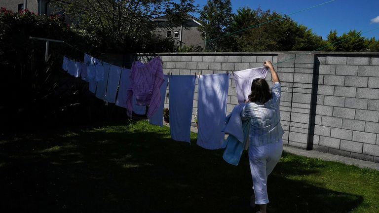 A woman receives dry laundry from a washing line during fine weather in Galway, Ireland, August 8, 2020. REUTERS / Clodagh Kilcoyne