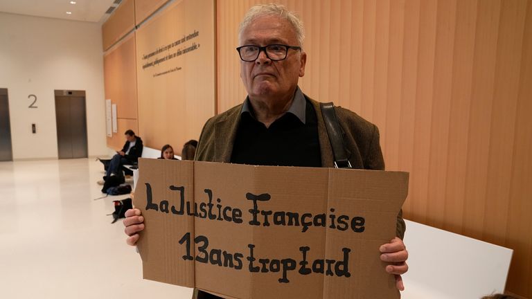 A man holds a placard reading &#39;The French justice, 13 years too late&#39; prior to the start of the trial. Pic: AP