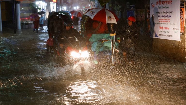 People ride rickshaws and motorcycle on a flooded street, amid continuous rain before the Cyclone Sitrang hits the country in Dhaka, Bangladesh