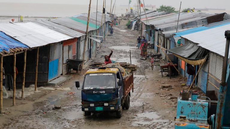 A man in the back of a mini truck waves to the camera as he drives away after evacuating valuables on the Bay of Bengal coast.  Boats secure their boats as they wait out the storm in Patenga, Chittagong, Monday, Oct. 24, 2022. Bangladeshi authorities evacuated hundreds of thousands of people across the vast coastal region on Monday as the tropical storm approached amid fears of widespread damage.  (AP Photo)